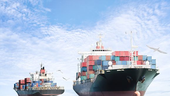 Container Frachtschiff im Ozean mit V√∂geln am blauen Himmel, Frachttransport.
