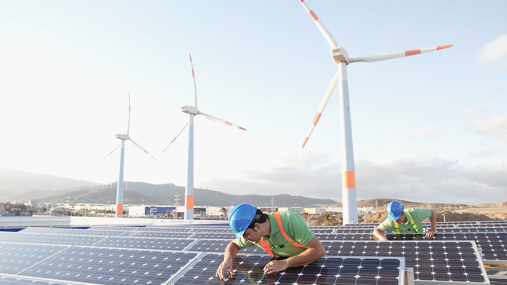 Bild von Arbeitern, die Sonnenkollektoren bei einem Plan fuer erneuerbare Energien inspizieren.