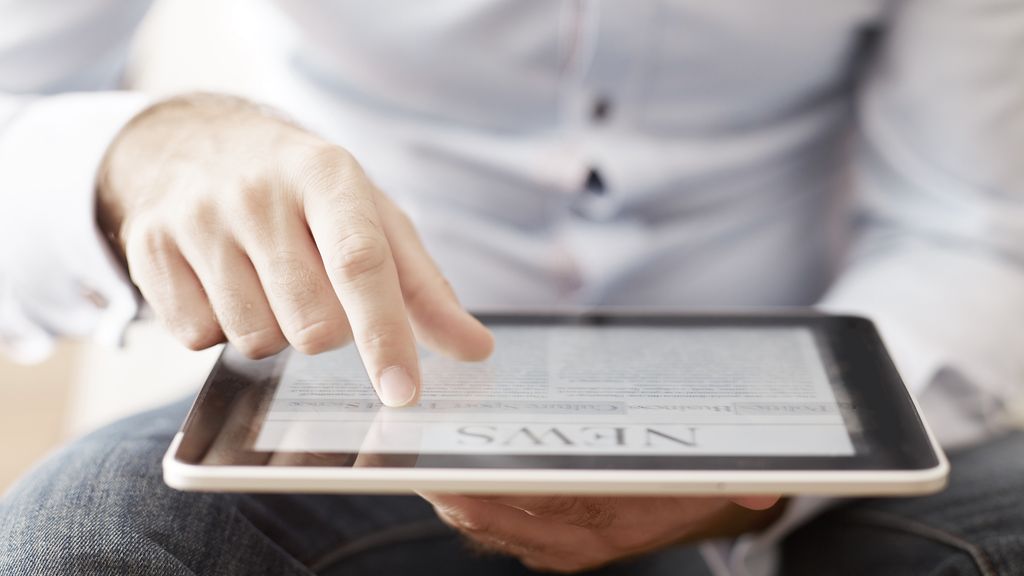 Mann hält einen Tablet-PC und liest Nachrichten